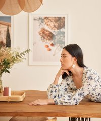 model wearing white hollandia floral smocked blouse resting against table
