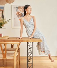 model in hvv atelier allons floral ruffle maxi dress in blue seated on table