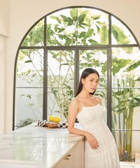 model wearing white floral embroidered maxi dress leaning against counter
