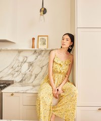 model in daffodil colour floral ruffle jumpsuit leaning against cupboard