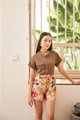 Model standing by window in Amie Floral Shorts and Caville Cuff Sleeve Blouse