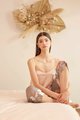 model sitting on bed in satin pink camisole and olive grey floral satin pants